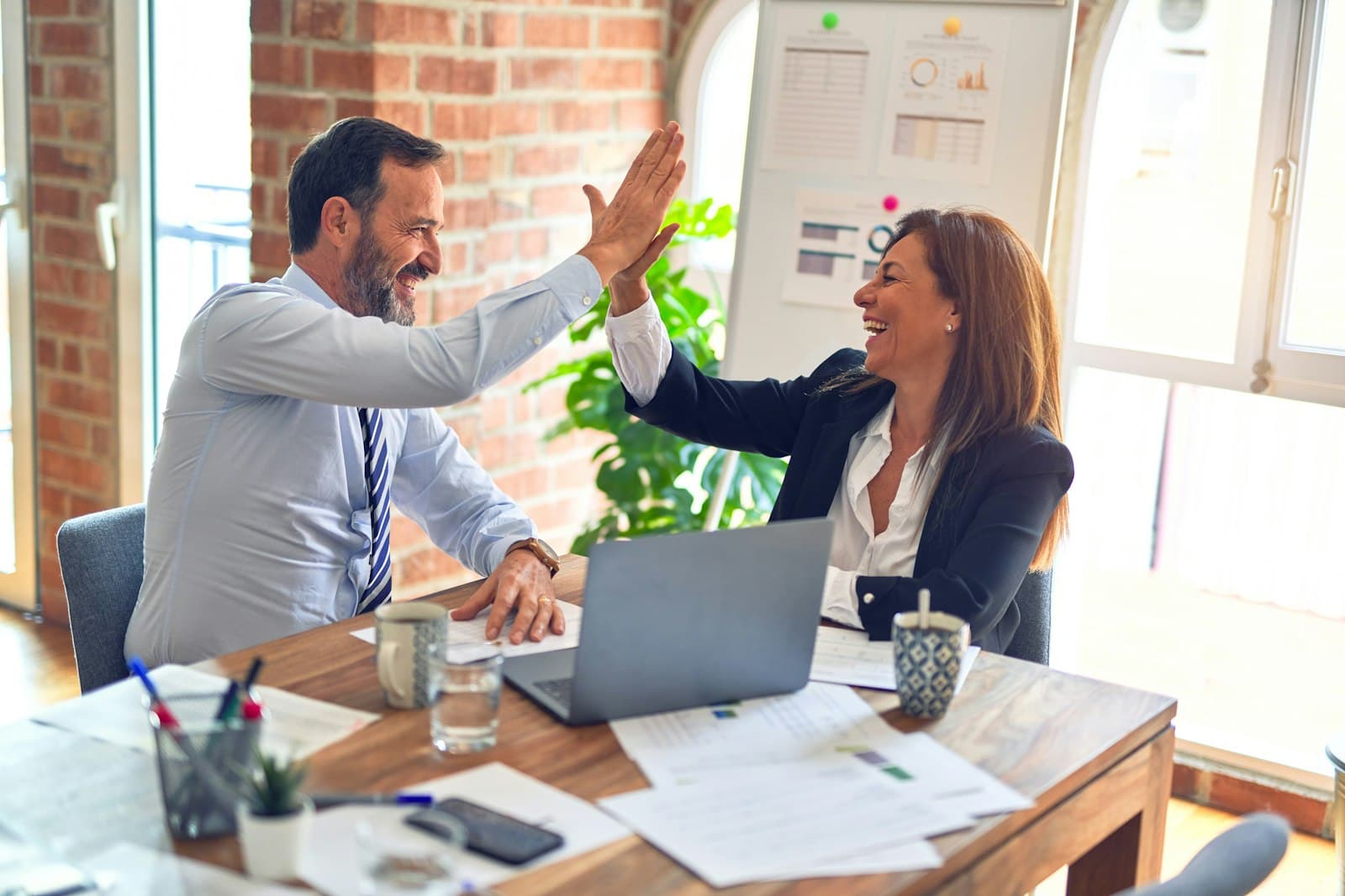 Two colleagues high-fiving at their desk